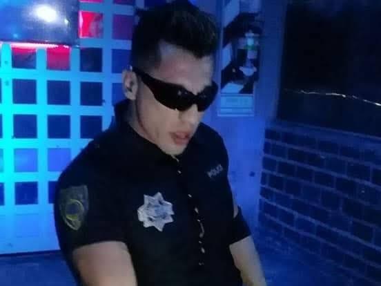 Pablo caracterizado de policía, con gafas de sol, bajo luz azul de sala.