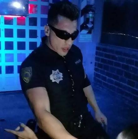 Pablo caracterizado de policía, con gafas de sol, bajo luz azul de sala.